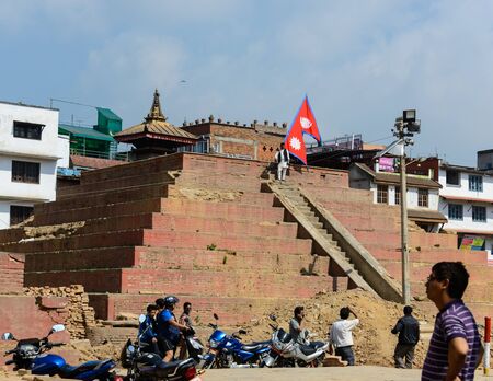 KATHMANDU, NEPAL - MAY 14, 2015: A man carries a large Nepal flag on Durbar Square, a UNESCO World Heritage Site.のeditorial素材