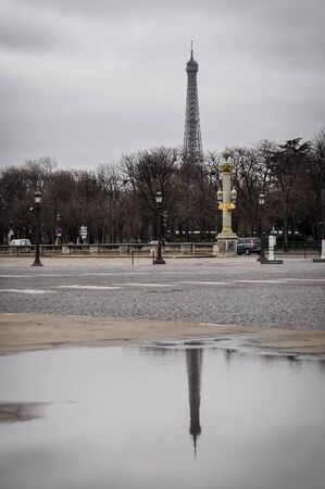 The Eiffel Tower and his reflection in a puddle as seen from the Concorde Square in Paris, France. Winter season.の写真素材