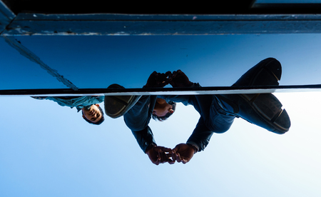 KATHMANDU, NEPAL - NOVEMBER 18, 2015: Two men travel on a bus roof. For roughly two months Nepal has been facing fuel shortage, as a result people are once again allowed to travel on bus roofs.のeditorial素材