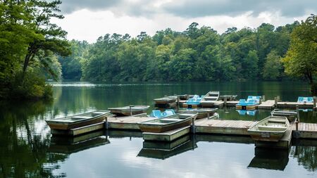 Aluminium bass fishing boat and pedalos at wooden dock in Virginia, America USAの写真素材