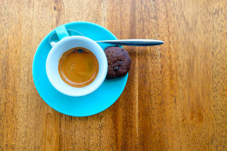 An espresso in a turquoise cup on a wood tableの写真素材