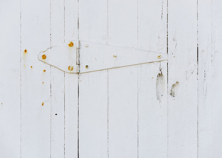 White wooden door hinge and rusty screws