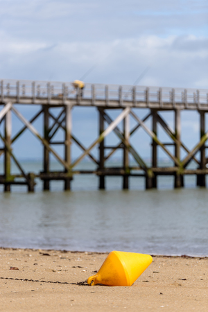 Orange buoy on the beach in Noirmoutier, pier in the backgroundの写真素材
