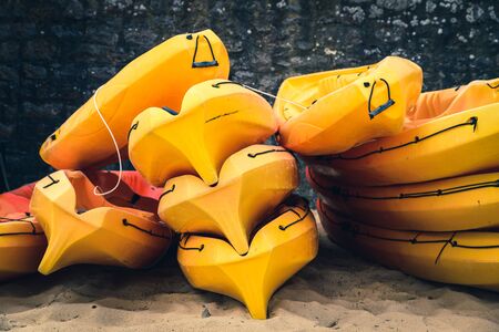 Stacked orange kayaks on a beach