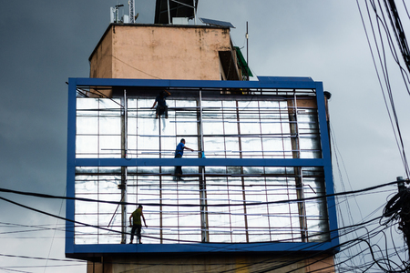 PATAN, NEPAL - CIRCA JULY 2017: Men working on a billboard with menacing monsoon cloud in the background.のeditorial素材