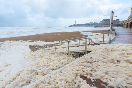 Foam on the Grande Plage beach and its quay during a storm, Franceの写真素材