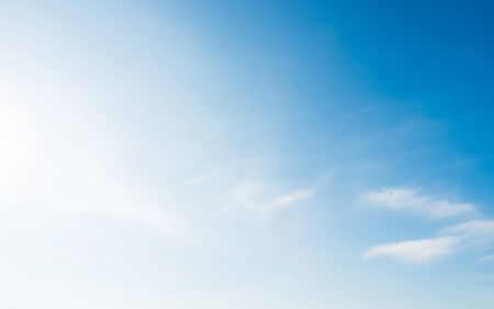Soft blue sky with small white clouds and bright sun lightの写真素材