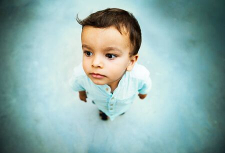 Little boy high angle shot portrait with shallow depth of field, grungy blue tone concrete floor...