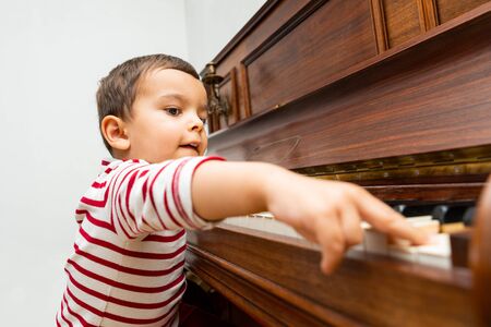Litlle boy playing the piano, toddler learning music at homeの写真素材
