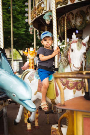Little boy rides a traditional carousel white horseの写真素材