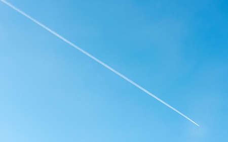 Diagonal contrail of jet plane flying in blue sky