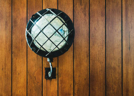 Vintage electric lamp on wooden wall, old sailboat lighting equipment.の写真素材