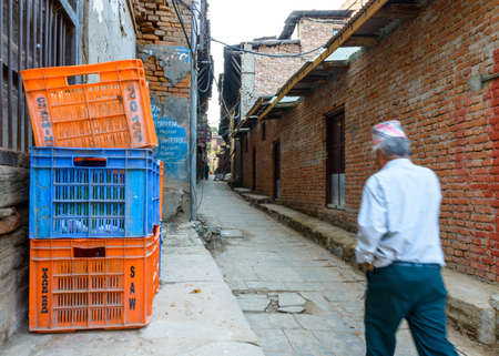 BHAKTAPUR, NEPAL - CIRCA NOVEMBER 2015: Nepalese man wearing a topi walks down a small alley. With motion blur.のeditorial素材