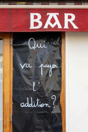 ESPELETTE, FRANCE - 21 FEBRUARY, 2021: Banner at Pottoka restaurant reads who is going to pay the bill. Restaurants and bars in France are closed since 29 October, 2020 to curb the Covid-19 pandemic.のeditorial素材