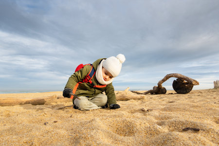 Little boy playing in the sand on beach in winterの写真素材