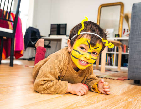 Little boy with bee face paint and playing at homeの写真素材