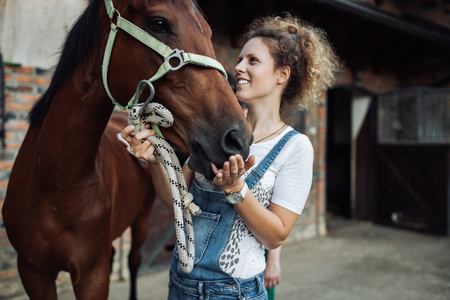 Young woman taking care of her beautiful horse.の写真素材