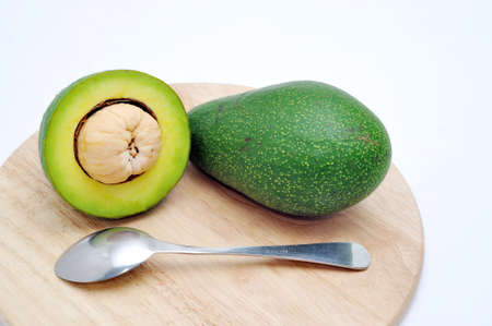 Avocado on the cutting board with spoon in a white backgroundの写真素材