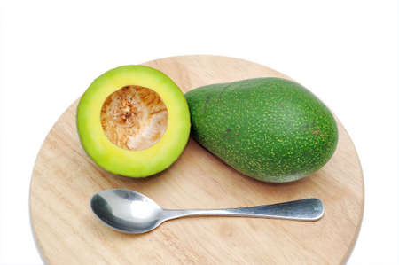 Avocado on the cutting board with spoon in a white backgroundの写真素材