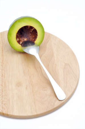 Avocado on the cutting board with spoon in a white backgroundの写真素材