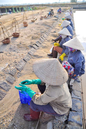NINH HOA, VIETNAM - MARCH 2, 2012: Vietnamese women salt workers are relaxing after working hard to collect salt from the extract fields to the storage fieldsのeditorial素材