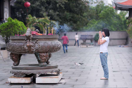 HO CHI MINH CITY, VIETNAM - AUGUST 14, 2010 - A young girl is praying in a pagoda in Saigonのeditorial素材