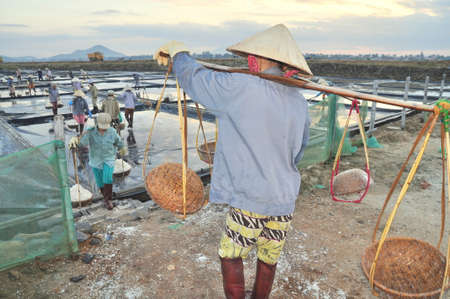 NINH HOA, VIETNAM - MARCH 2, 2012: Vietnamese women are burdening hard to collect salt from the extract fields to the storage fieldsのeditorial素材