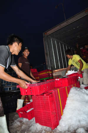 NHA TRANG, VIETNAM - FEBRUARY 21, 2013: Porters at the Hon Ro seaport are loading baskets of fishes...