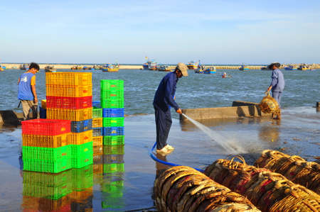 LAGI, VIETNAM - FEBRUARY 26, 2012: A local man is cleaning his baskets which were used for transporting fishes from the boat to the truckのeditorial素材