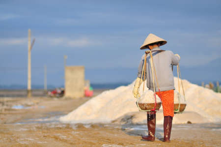 NINH HOA, VIETNAM - MARCH 2, 2012: Vietnamese women are burdening hard to collect salt from the extract fields to the storage fieldsのeditorial素材