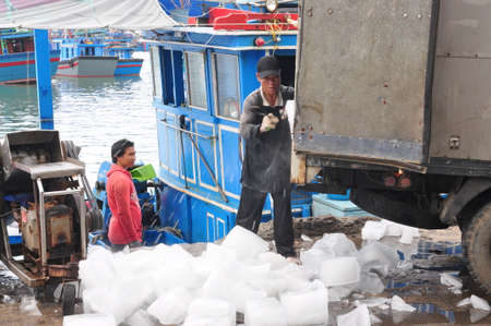 NHA TRANG, VIETNAM - FEBRUARY 21, 2013:  Workers are grinding ice to preserve tuna fish in the Hon Ro seaport, Nha Trang cityのeditorial素材
