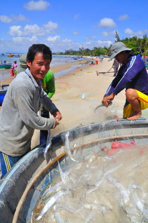 LAGI, VIETNAM - FEBRUARY 26, 2012: Local fishermen are removing fishes from their fishing nets in the Lagi beachのeditorial素材