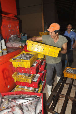 HO CHI MINH CITY, VIETNAM - NOVEMBER 28, 2013: Porters are working hard to load plenty baskets of fisheries at the Binh Dien wholesale night seafood market, the biggest one in Vietnamのeditorial素材