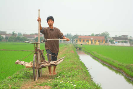 NAM DINH, VIETNAM - MARCH 28, 2010: A farmer in the north of vietnam is going to work on his paddy fieldのeditorial素材