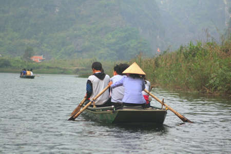 NINH BINH, VIETNAM - MARCH 29, 2010: Ferrymen are taking tourists to visit the Trang An Eco-Tourism Complex, a complex beauty - landscapes called as an outdoor geological museumのeditorial素材