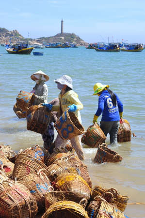 LAGI, VIETNAM - FEBRUARY 26, 2012: Local women are cleaning their baskets which were used for transporting fishes from the boat to the truckのeditorial素材