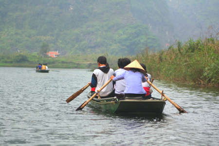 NINH BINH, VIETNAM - MARCH 29, 2010: Ferrymen are taking tourists to visit the Trang An Eco-Tourism Complex, a complex beauty - landscapes called as an outdoor geological museumのeditorial素材