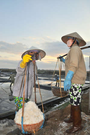 NINH HOA, VIETNAM - MARCH 2, 2012: Vietnamese women are burdening hard to collect salt from the extract fields to the storage fieldsのeditorial素材