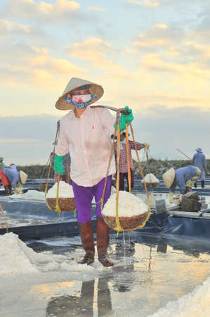 NINH HOA, VIETNAM - MARCH 2, 2012: Vietnamese women are burdening hard to collect salt from the extract fields to the storage fieldsのeditorial素材