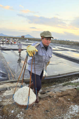 NINH HOA, VIETNAM - MARCH 2, 2012: Vietnamese women are burdening hard to collect salt from the extract fields to the storage fieldsのeditorial素材