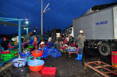 NHA TRANG, VIETNAM - FEBRUARY 21, 2013: Porters at the Hon Ro seaport are loading baskets of fishes onto the truck to a local processing plant in Nha Trang cityのeditorial素材