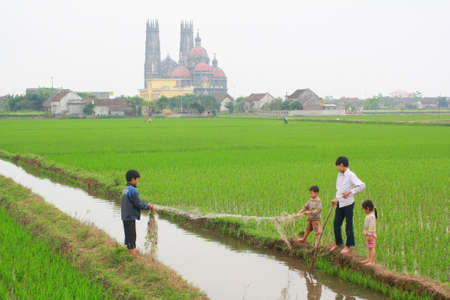 NAM DINH, VIETNAM - MARCH 28, 2010: Children are playing in the paddy field in the countryside of the North of Vietnamのeditorial素材