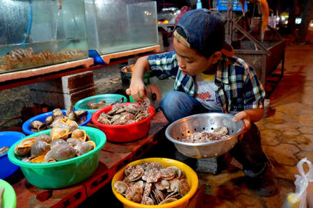 Saigon, Vietnam - February 1, 2016: A child is selecting shells for eating in a street food vendor in Vietnamのeditorial素材