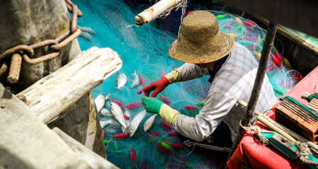 Tien Giang, Vietnam - January 10, 2016: A fisherman is taking his fish from the fishing net in the Mekong river in Vietnamのeditorial素材
