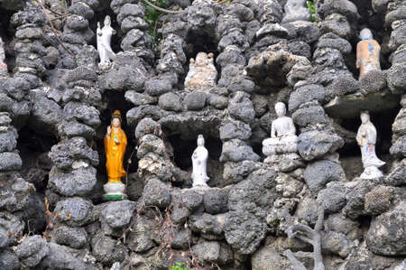 Cam Ranh, Vietnam - February 9, 2016: Many buddha statues are put in plenty of small holes in a wall made of seashell in a pagoda in Vietnamのeditorial素材