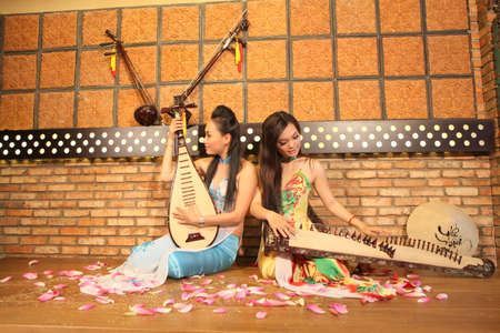 Vinh Long, Vietnam - November 4, 2015: Two young girls are playing Vietnamese traditional instruments in a restaurantのeditorial素材