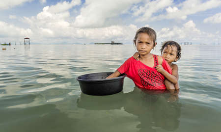 Mekong, Thailand - June 27, 2016: A young sister with her brother is catching fish in the Mekong riverのeditorial素材