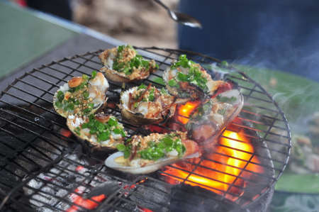 Grilling shellfish and seafood on hot fireの写真素材