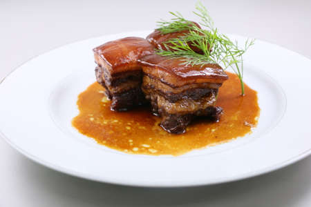 Braised pork meat in Chinese style with herbs on white plateの写真素材