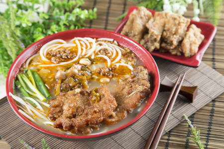 Chinese bowl of noodle with fried pork ribs and herbs on the tableの写真素材